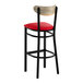 A bar stool with a black metal frame, red vinyl seat, and a driftwood-finished curved backrest.