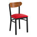 A black metal chair with a red vinyl seat and a curved vintage wood backrest.