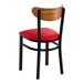 A black metal chair with a red vinyl seat and a curved vintage wood backrest.