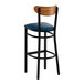 A bar stool with a black metal frame, navy vinyl seat, and a curved vintage wood backrest.