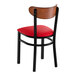 A black metal chair with a red vinyl seat and an antique walnut wood backrest.