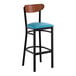 A black metal bar stool with a blue vinyl seat and an antique walnut wood backrest.