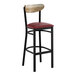 A black bar stool with a burgundy vinyl seat and a driftwood-finished wooden backrest.