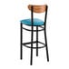 A black metal bar stool with a blue vinyl seat and a curved wooden backrest.