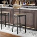 A black finish bar stool with a driftwood seat and back, featuring a modern design.