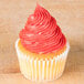 A vanilla cupcake with red frosting piped in a swirl using a French star piping tip.