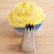 A stainless steel open star piping tip labeled 'Ateco 828' is shown in front of a cupcake with yellow frosting.