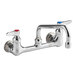 A chrome T&S wall mount faucet with two handles and two faucets.