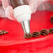 A closed star piping tip being used to decorate a cake with chocolate icing.