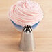 A stainless steel closed star piping tip is shown in front of a cupcake with pink frosting.