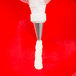 An open star piping tip being used to pipe icing onto a red surface.