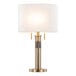 A gold table lamp with a white linen drum shade and a cylindrical base.
