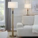 A gold table lamp with a white linen drum shade.