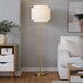 A gold floor lamp with an off-white tiered linen shade.