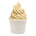 A serving of light brown soft-serve frozen yogurt in a plain white paper cup.