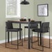 A set of two high-back barstools with black steel frames and black faux leather seats and backs.