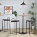 A pair of black metal barstools with low backs and brown faux leather seats.