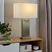 A rectangular table lamp with an antique brass base and a white linen shade.