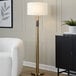 A gold floor lamp with a white linen drum shade.
