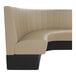 A large, curved beige booth with vertical channel stitching and a black base, designed for seating in commercial spaces.