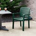 A green Grosfillex Acadia chair on a concrete patio next to a table with drinks.