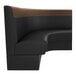 A large, curved cafe booth with a high backrest, featuring black upholstery and a brown head roll accent.