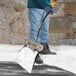 A 20-inch aluminum blade snow shovel with a wear strip and ergonomic D-grip handle being used to clear snow.