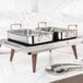 A stainless steel warming shelf with two rectangular pans and wooden legs, designed for keeping food warm.