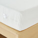 A white waterproof poly knit mattress protector fitted on a California king bed.