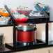 A black Carlisle adjustable single sneeze guard over a buffet counter.