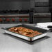 A Vollrath stainless steel steam table pan filled with food on a counter.