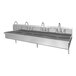 A stainless steel four-person wall mount sink with four faucets.