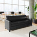 A black leather sofa with three seats, wooden feet, and built-in charging banks.