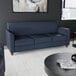 A navy blue three-seat sofa with wooden feet and a modern design.
