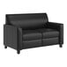 A black leather loveseat with wooden feet and a charging bank.