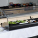 A Carlisle black standard sneeze guard covering a salad bar on a buffet table.