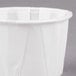 A Solo white paper souffle cup on a grey surface.