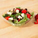 A salad with strawberries and cheese in a Sabert clear plastic container.