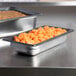 A Vollrath stainless steel steam table pan with food on a counter.