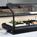 A black Carlisle adjustable sneeze guard over a salad bar counter.