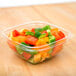 A clear Sabert catering bowl filled with chopped bell peppers.