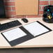 An Avery black economy view binder with 1/2 inch round rings, shown open on a desk with paper inside.