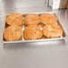 A quarter size aluminum bun or sheet pan holding six croissants.