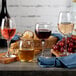 A table with Acopa wine glasses filled with red and pink wine, surrounded by grapes.