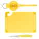 A yellow Saf-T-Grip plastic cutting board with a knife and spoon.