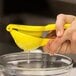 A person squeezing lemon juice into a yellow bowl.