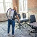A cordless backpack vacuum being used to clean an office carpet.