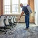 A cordless backpack vacuum cleaner being used to clean a carpeted office space.