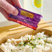 A packet of Lee Kum Kee Selected Aromatic Vinegar Seasoning being poured over a serving of rice.