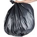 A person holding a Berry low density black trash bag.